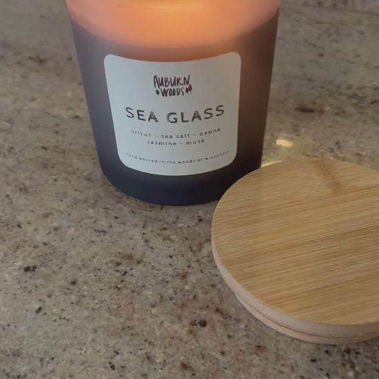 sea glass candle burning. smells like citrus, sea salt, jasmine, ozone. coconut wax, cottoon wick